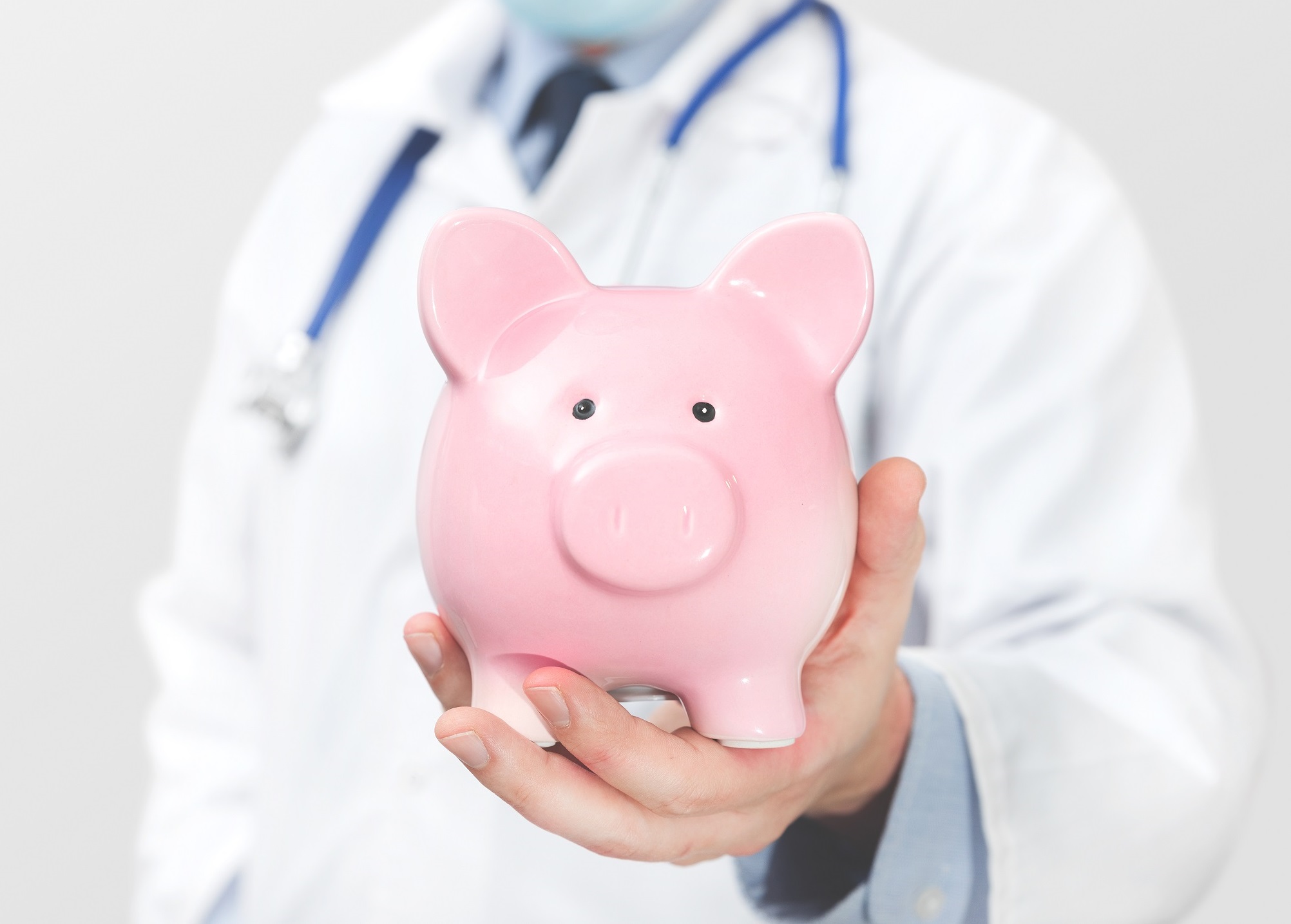 A doctor holding a piggy bank.