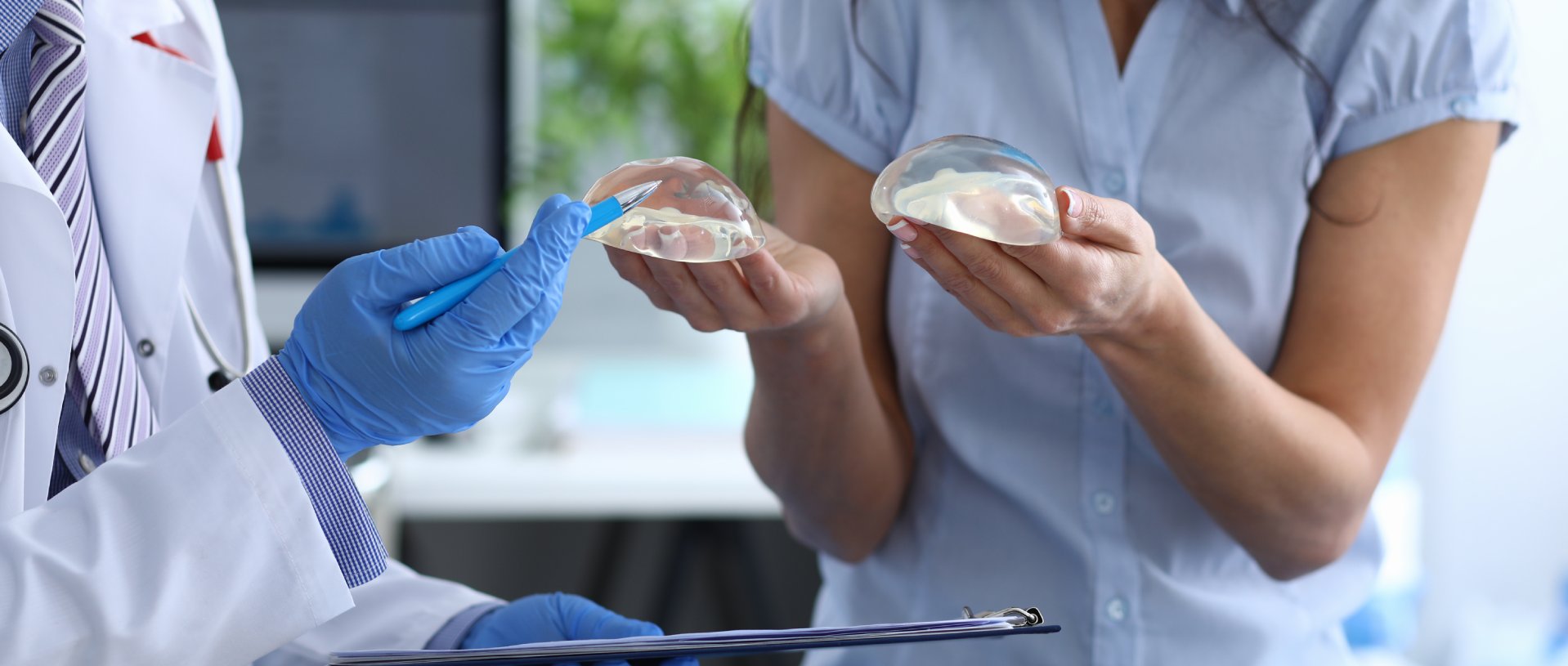 plastic surgeon shows female patient breast implant samples for her future surgery