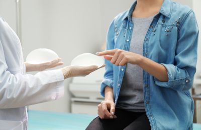 A plastic surgeon discussing and showing recommended breast implant type and size to a woman who is considering breast augmentation surgery.